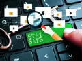 Un dedo presiona "STAY SAFE" en un teclado. Iconos de sobres con candados y arañas sugieren un enlace seguro y amenazas.