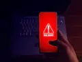 Alerta en el móvil: el teléfono muestra un aviso de "MALWARE" en rojo, indicando el peligro de apps maliciosas.
