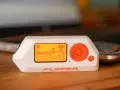El Flipper Zero, un dispositivo portátil con pantalla naranja que muestra una escena de playa, es una herramienta versátil para explorar la tecnología.