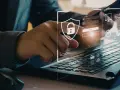 Persona interactuando con una interfaz digital de seguridad empresarial, mostrando un candado y datos.
