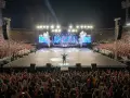 Artista en un estadio ante miles de fans. La multitud levanta sus teléfonos, como si quisieran saber **como ver ubicación en tiempo real** de sus amigos en el concierto.