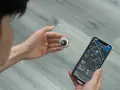 Persona revisa un AirTag y un iPhone con mapa. Aprende como saber si rastrean mi iPhone con esta tecnología.
