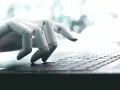 Mano robótica escribiendo en un teclado, una imagen que ilustra qué son los bots y su interacción con la tecnología.