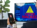 Un hombre recibe una llamada de un número desconocido mientras en la pantalla se lee "SYSTEM HACKED". ¡He sido hackeado!