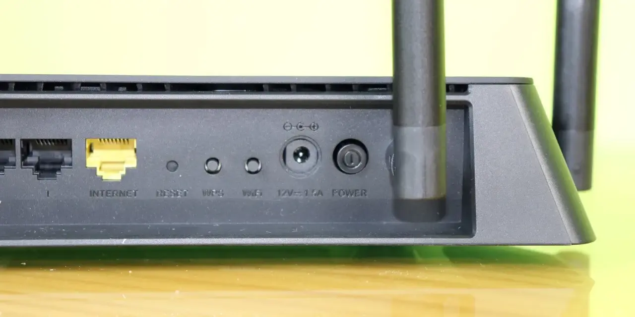 Detalle de un router con puertos Ethernet, botón de reinicio y conexión de energía. Ideal para quienes necesitan reiniciar router.
