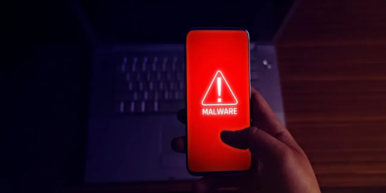 Alerta en el móvil: el teléfono muestra un aviso de "MALWARE" en rojo, indicando el peligro de apps maliciosas.