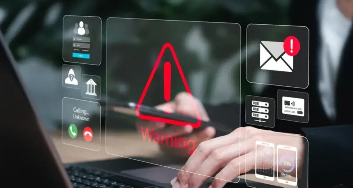 Alerta de seguridad digital: un mensaje falso podría estar acechando. Iconos de advertencia, correo, tarjetas y teléfonos flotan sobre un portátil.