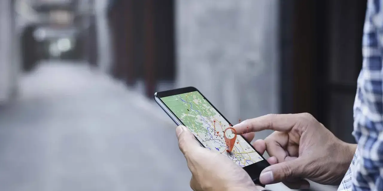 Hombre usando su móvil para localizar una persona por móvil en un mapa.