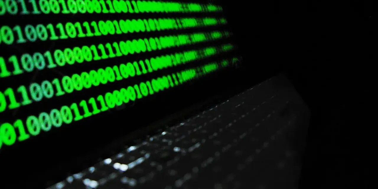 Código binario verde en pantalla, reflejando un teclado. ¿Qué es idp.generic? Es la base de la información digital.