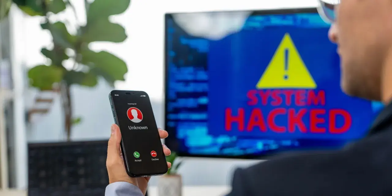 Un hombre recibe una llamada de un número desconocido mientras en la pantalla se lee "SYSTEM HACKED". ¡He sido hackeado!