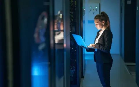 Mujer con portátil en centro de datos, gestionando infraestructura como servicio (IaaS) y soluciones SOC as a service.