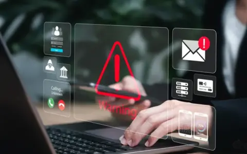Alerta de seguridad digital: un mensaje falso podría estar acechando. Iconos de advertencia, correo, tarjetas y teléfonos flotan sobre un portátil.