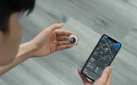 Persona revisa un AirTag y un iPhone con mapa. Aprende como saber si rastrean mi iPhone con esta tecnología.