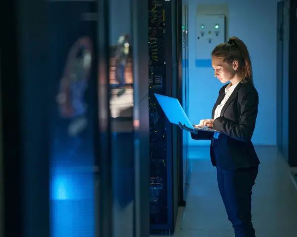 Mujer con portátil en centro de datos, gestionando infraestructura como servicio (IaaS) y soluciones SOC as a service.