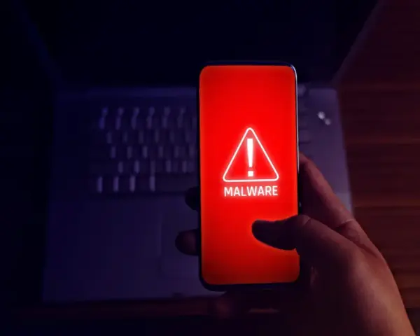 Alerta en el móvil: el teléfono muestra un aviso de "MALWARE" en rojo, indicando el peligro de apps maliciosas.