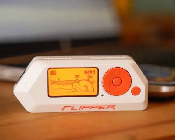 El Flipper Zero, un dispositivo portátil con pantalla naranja que muestra una escena de playa, es una herramienta versátil para explorar la tecnología.
