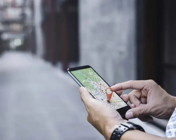 Hombre usando su móvil para localizar una persona por móvil en un mapa.