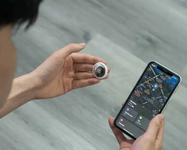 Persona revisa un AirTag y un iPhone con mapa. Aprende como saber si rastrean mi iPhone con esta tecnología.