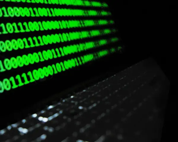 Código binario verde en pantalla, reflejando un teclado. ¿Qué es idp.generic? Es la base de la información digital.