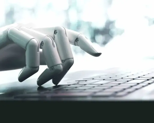 Mano robótica escribiendo en un teclado, una imagen que ilustra qué son los bots y su interacción con la tecnología.