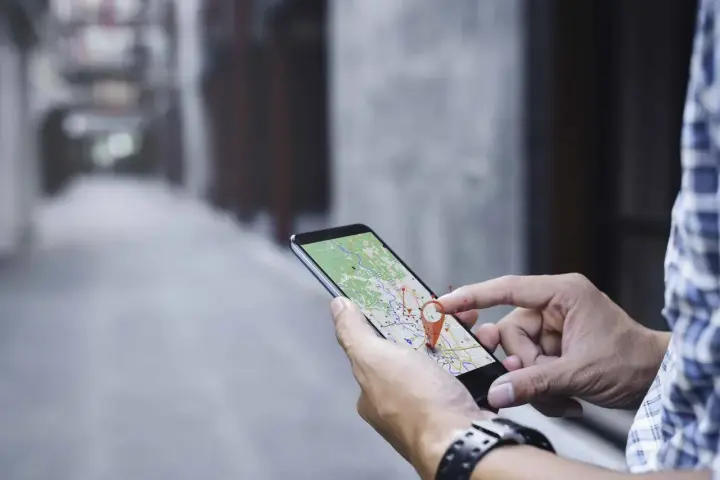 Hombre usando su móvil para localizar una persona por móvil en un mapa.