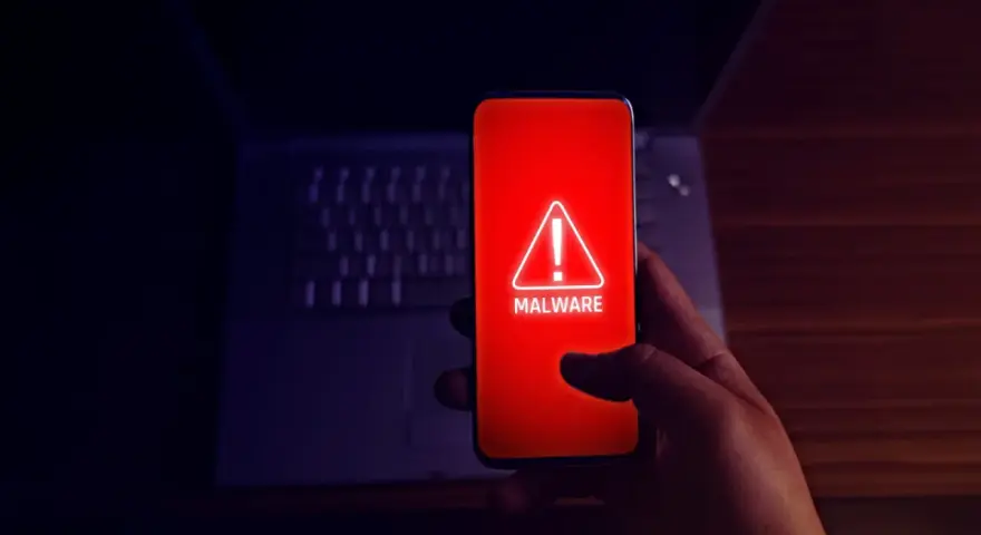 Alerta en el móvil: el teléfono muestra un aviso de "MALWARE" en rojo, indicando el peligro de apps maliciosas.
