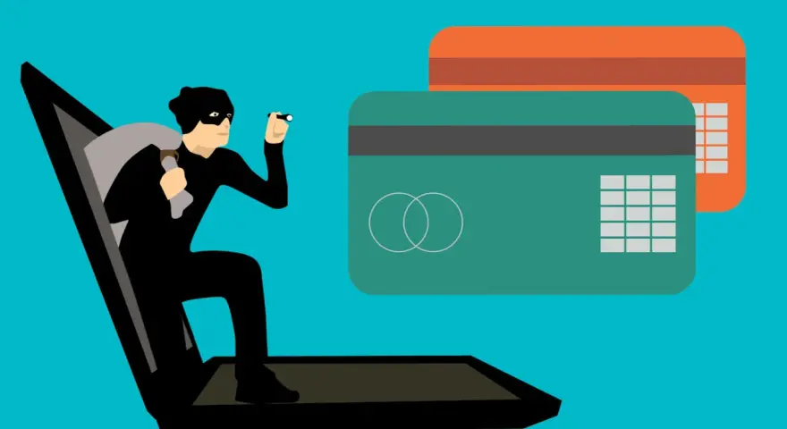 Ladrón sale de portátil con saco y linterna, cerca de tarjetas de crédito. Aprende como saber si una tienda online es falsa.