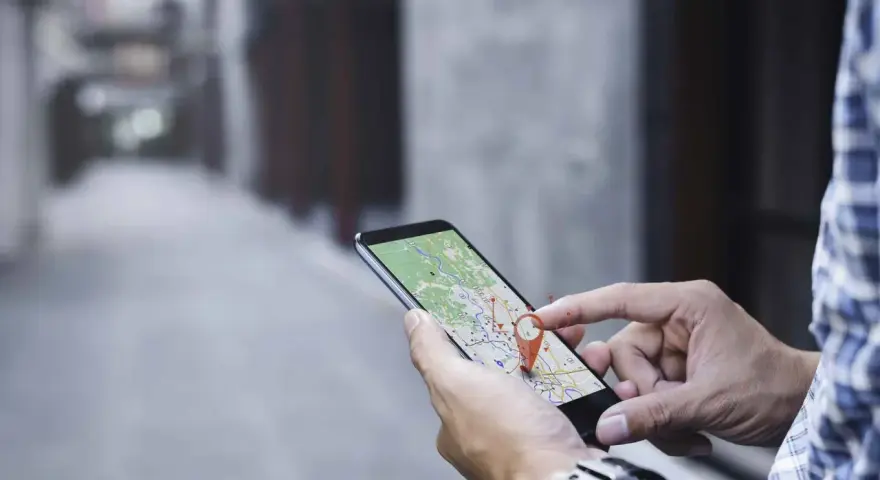 Hombre usando su móvil para localizar una persona por móvil en un mapa.