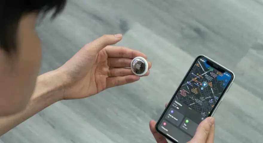 Persona revisa un AirTag y un iPhone con mapa. Aprende como saber si rastrean mi iPhone con esta tecnología.