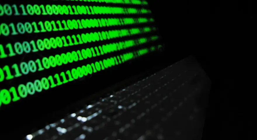 Código binario verde en pantalla, reflejando un teclado. ¿Qué es idp.generic? Es la base de la información digital.