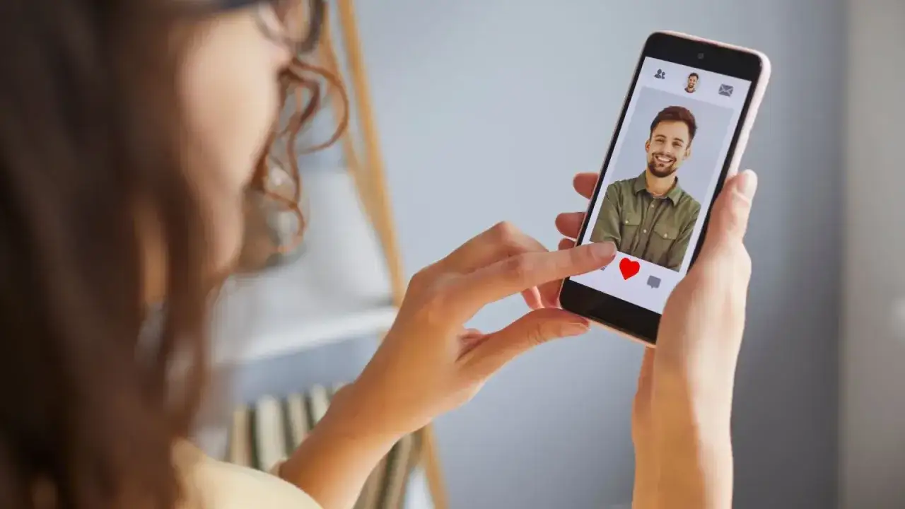 Mujer desliza el dedo en un teléfono móvil, viendo un perfil de citas. ¿Será uno de esos perfiles falsos de Meetic?