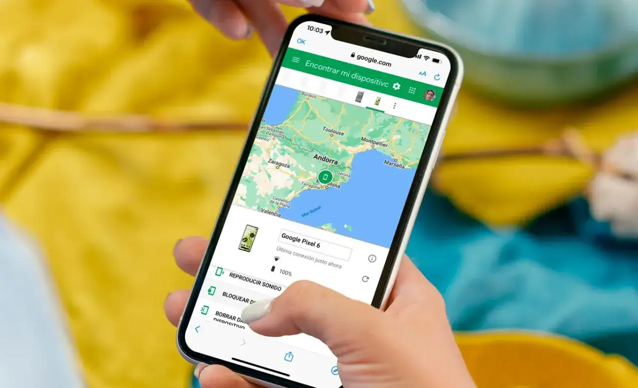 Mano usando un rastreador de tel&eacute;fono en un iPhone para localizar un Google Pixel 6 en el mapa de Espa&ntilde;a.
